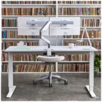 A Humanscale Float sit-to-stand table with a black frame and a white top. The table is adjustable in height, so you can switch from sitting to standing throughout the day.